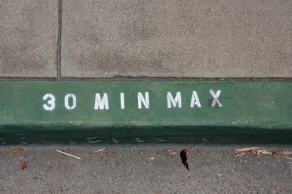 Close-up on green painted curb with '30 min max' in white.